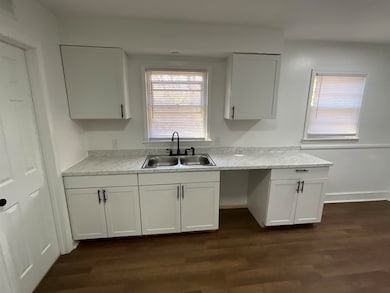 Kitchen featuring sink, white cabinetry, and dark 