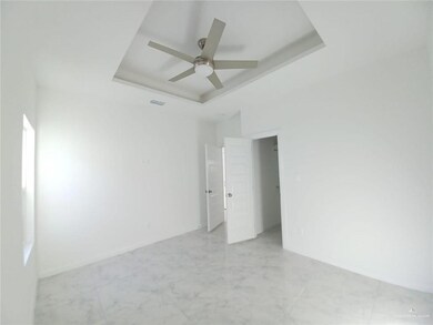 Unfurnished room featuring a raised ceiling, a ceiling fan, and light marble finish floors