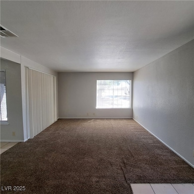 Carpeted empty room with visible vents, a textured