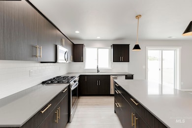 Kitchen with appliances with stainless steel finishes, backsplash, decorative light fixtures, recessed lighting, and modern cabinets