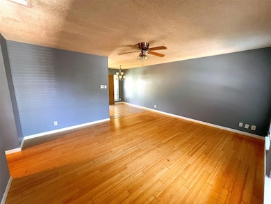 Spare room featuring a textured ceiling, a ceiling fan, a chandelier, and light wood-type flooring