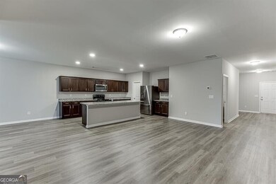Kitchen featuring open floor plan, appliances with stainless steel finishes, light wood-style flooring, a kitchen island with sink, and recessed lighting