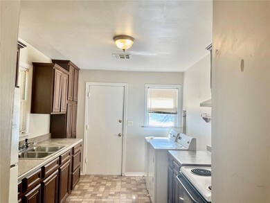 Kitchen featuring white range with electric cooktop, washing machine and clothes dryer, and sink