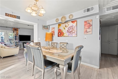 Dining area with light wood-style floors, a chandelier, and french doors