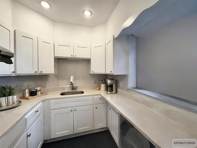 Kitchen with light countertops, white cabinetry, recessed lighting, and ventilation hood