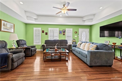 Living area featuring ceiling fan, wood finished floors, recessed lighting, and a tray ceiling