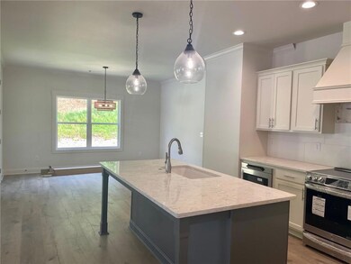 Kitchen featuring premium range hood, backsplash, a center island with sink, sink, and stainless steel range with electric cooktop