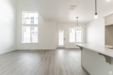 Unfurnished living room featuring light wood-style floors, a textured ceiling, and a chandelier