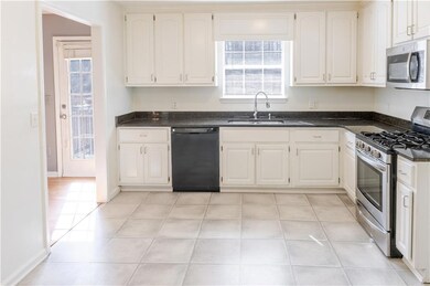 Kitchen with a sink, dark countertops, appliances 