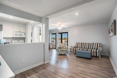 Living room featuring a textured ceiling, wood finished floors, recessed lighting, and a ceiling fan