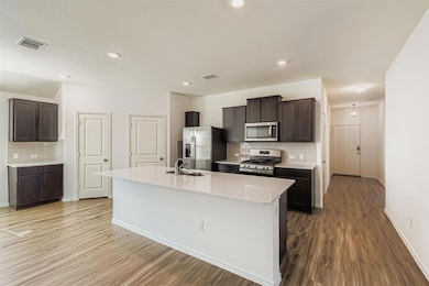 Kitchen featuring decorative backsplash, stainless steel appliances, dark wood finished floors, dark brown cabinetry, and recessed lighting