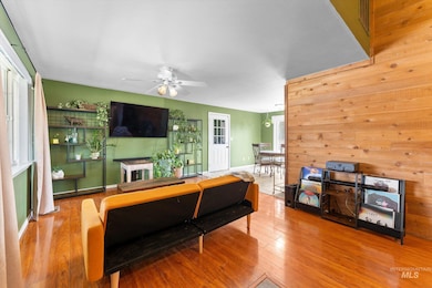 Living area with wood walls, wood finished floors, and a ceiling fan