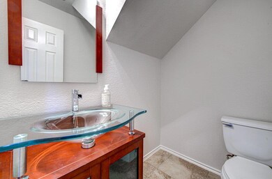Half bath with a textured wall, vanity, a textured ceiling, and lofted ceiling