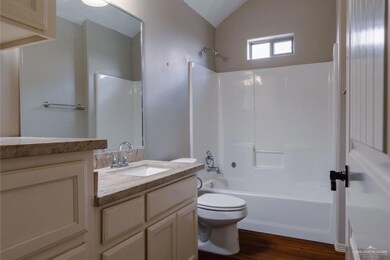 Full bathroom featuring shower / bathing tub combination, vanity, lofted ceiling, hardwood / wood-style flooring, and toilet