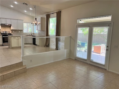 Kitchen with light tile patterned floors, light countertops, stainless steel range, decorative backsplash, and white cabinets