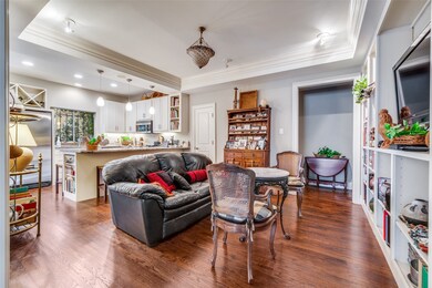 Living area with a raised ceiling, crown molding, dark wood finished floors, and recessed lighting