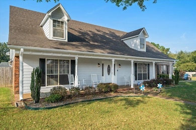 New england style home with a porch, a front yard, and a shingled roof