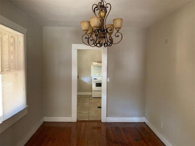 Unfurnished dining area featuring a chandelier, wood finished floors, healthy amount of natural light, and baseboards