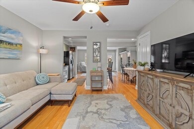 Living room with ceiling fan and light hardwood / 