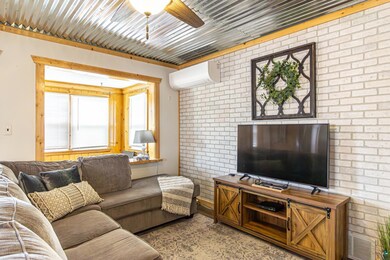 Living room with an AC wall unit, ceiling fan, and