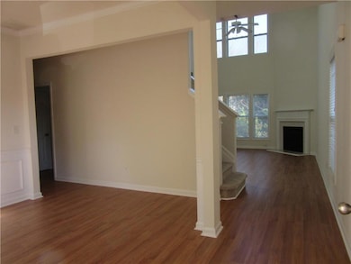 Unfurnished living room with a towering ceiling, dark wood finished floors, healthy amount of natural light, a fireplace, and stairway