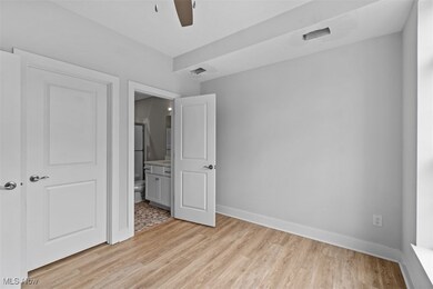 Unfurnished bedroom with connected bathroom and light wood-type flooring