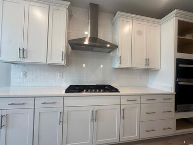 Kitchen featuring white cabinets, wall chimney ran