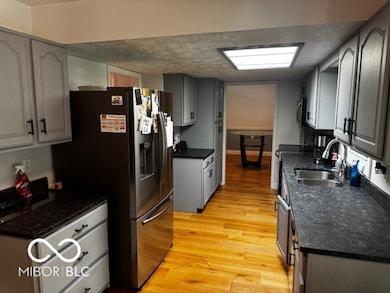 kitchen with stainless steel appliances, light wood-style floors, and a textured ceiling