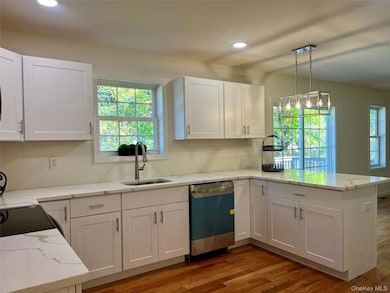 Kitchen with white cabinets, dark wood-style floors, a peninsula, light stone counters, and recessed lighting