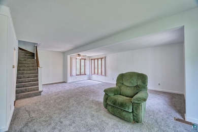 Sitting room featuring carpet flooring, stairs, ceiling fan, a textured ceiling, and baseboards