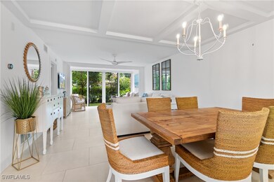 Dining space featuring beam ceiling, light tile patterned floors, and ceiling fan with notable chandelier
