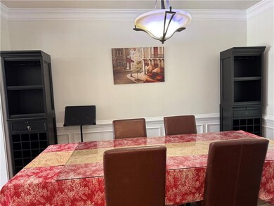 Dining room with ornamental molding, a decorative wall, and a wainscoted wall