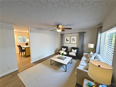 Living room with wood finished floors, a ceiling fan, and a textured ceiling