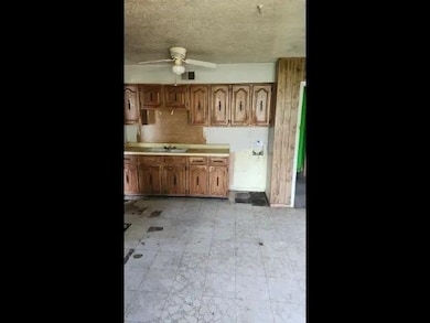 Kitchen featuring ceiling fan, light countertops, a textured ceiling, brown cabinets, and light floors
