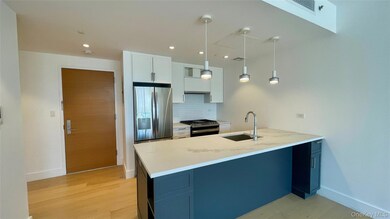 Kitchen with light stone countertops, stainless steel appliances, decorative light fixtures, white cabinets, and backsplash