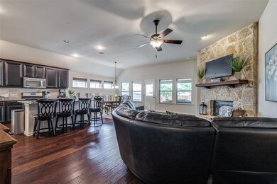 Living room with a stone fireplace, ceiling fan, a