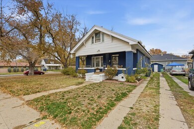 Bungalow with covered porch, a front lawn, and brick siding