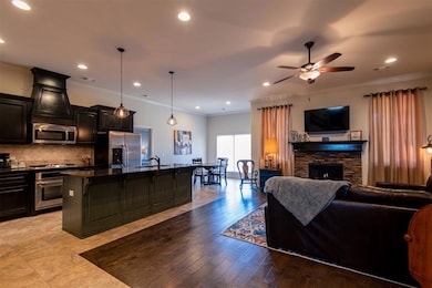 Kitchen with appliances with stainless steel finishes, open floor plan, a kitchen island with sink, a sink, and a ceiling fan