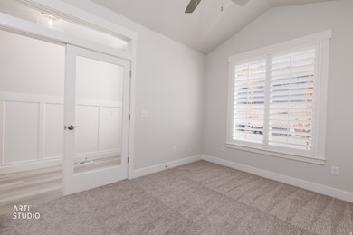 Unfurnished bedroom with vaulted ceiling, a ceiling fan, and carpet floors