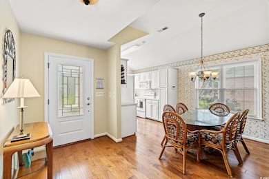 Dining room with a chandelier, light wood-style flooring, baseboards, and wallpapered walls