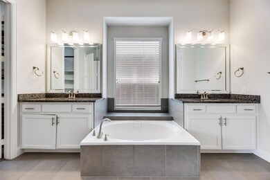 Primary Bathroom with tiled garden tub, tile floors, and double sink vanity