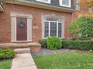 Entrance to property with brick siding, roof with shingles, mansard roof, and a lawn