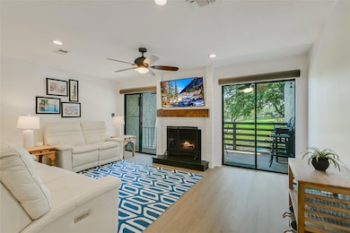 Living room featuring ceiling fan, a large firepl
