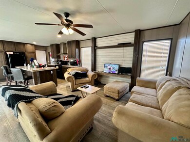Living room featuring wood walls, ceiling fan, light wood-type flooring, and a textured ceiling