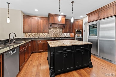 Kitchen featuring stainless steel appliances, backsplash, dark stone countertops, dark cabinetry, and recessed lighting