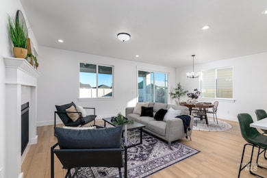 Living room featuring light wood finished floors, recessed lighting, a fireplace, and a chandelier