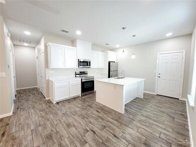 Kitchen featuring stainless steel appliances, a sink, light wood-type flooring, baseboards, and white cabinetry