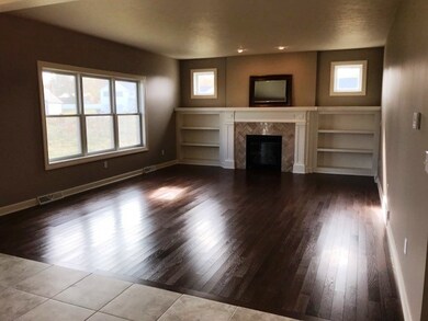 Living room with gleaming hardwood floor and built