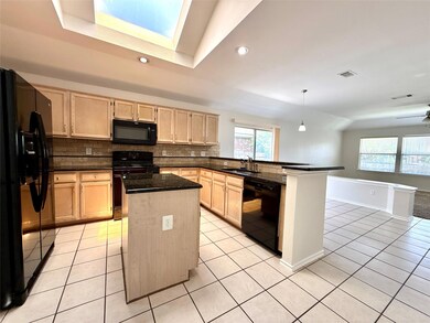 Kitchen featuring light brown cabinetry, black ap