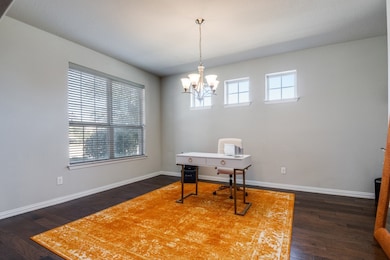 Home office featuring dark wood-style floors and a chandelier